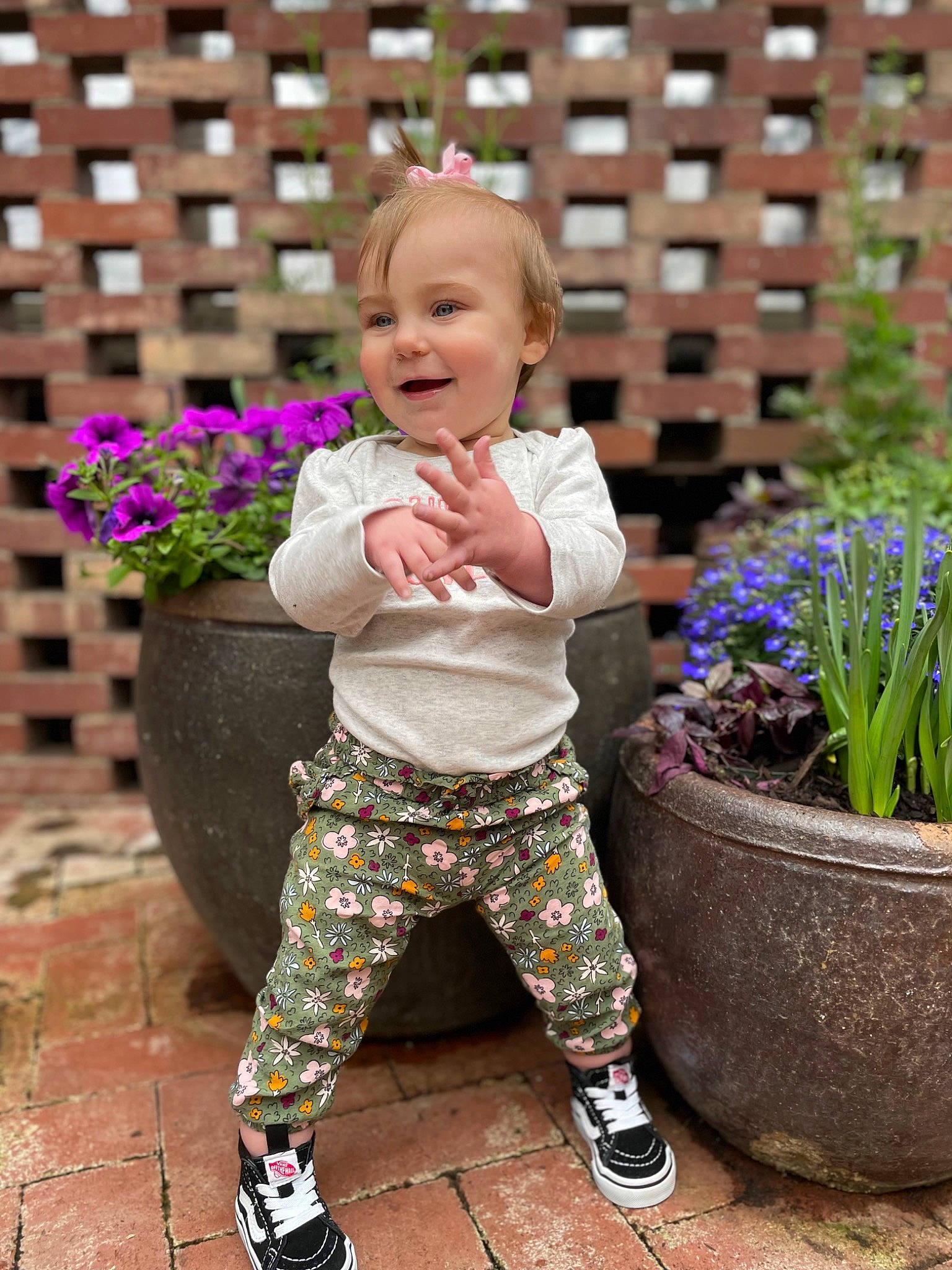 Karmyn is registered to the contest to win money with this photo: baby, baby_toddler_clothing, botany, eye, flower, flowerpot, grass, happy, head, houseplant, leaf, people_in_nature, person, pink, plant, purple, sleeve, smile, standing, summer
