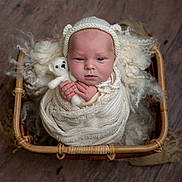 River joined the competition — help win amazing prizes! baby, newborn, infant, swaddled, knitted_bonnet, bear_ears, teddy_bear, wicker_basket, wool, soft_texture, wooden_floor, cute, portrait, indoors, child, sleepy, small_hands, cozy, wrapped, peaceful