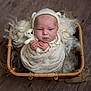 baby, newborn, infant, swaddled, knitted_bonnet, bear_ears, teddy_bear, wicker_basket, wool, soft_texture, wooden_floor, cute, portrait, indoors, child, sleepy, small_hands, cozy, wrapped, peaceful