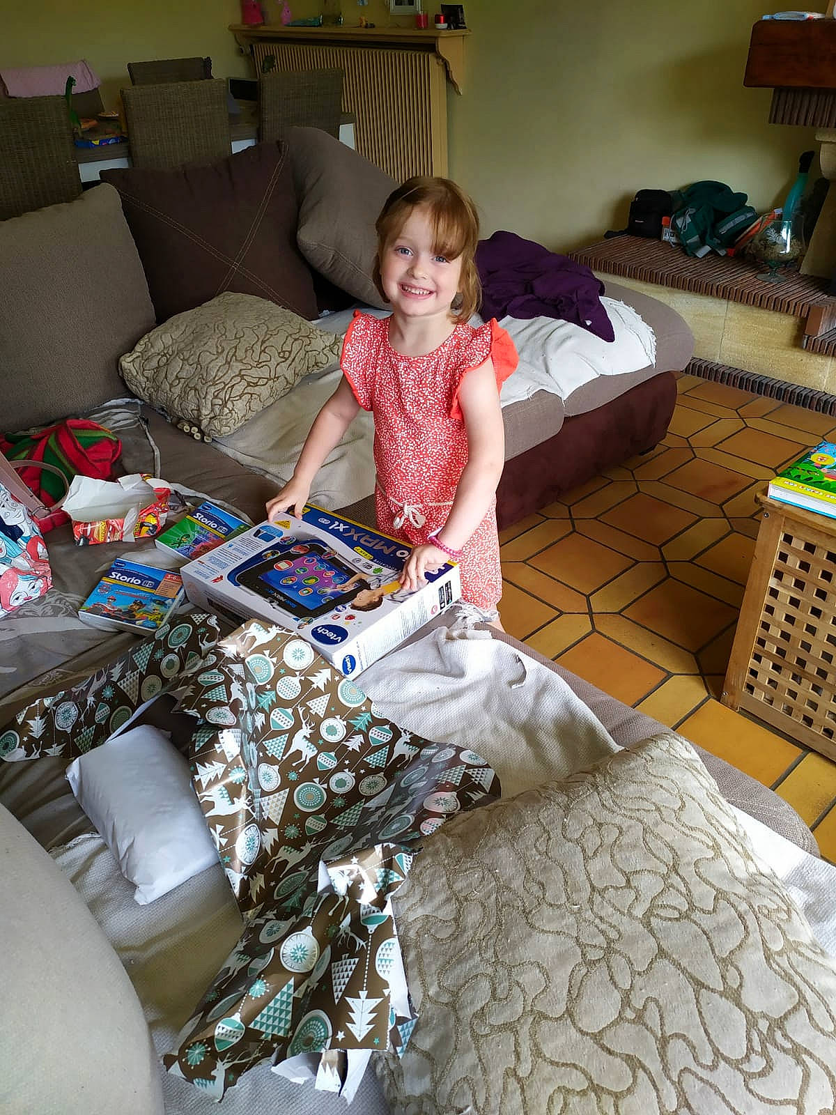 Lou-ann a rejoint le concours — aidez-le/la à gagner de superbes lots ! box, chest_of_drawers, child, comfort, couch, event, flooring, fun, furniture, joy, linens, living_room, pattern, person, pillow, play, room, sitting, smile, t_shirt