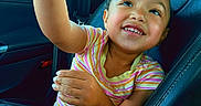 Adalyn joined the competition — help win amazing prizes! child, smiling, car_seat, striped_shirt, toy, happy, indoor, person, seatbelt, looking_up, curious, skin, hair, arm, hand, legs, car_interior, window, daylight, casual_clothing