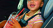 Adalyn is registered to the contest to win money with this photo: car_interior, car_seat, child, daylight, drink, face, gas_station, hair, hands, happy, pink_drink, red_straw, seatbelt, shorts, skin, slushie, smiling, striped_shirt, toddler, window