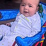 baby, child, infant, pajamas, star_pattern, blue_chair, foldable_chair, red_frame, curious_expression, indoors, seated, face, person, cute, soft_lighting, comfortable, small_hand, clothing, tag, background_blur