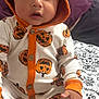 Ezekiel joined the competition — help win amazing prizes! baby, child, pumpkin, hoodie, onesie, orange, white, pattern, bedspread, hand, face, indoors, person, cute, expression, sitting, clothing, portrait, young_child, festive