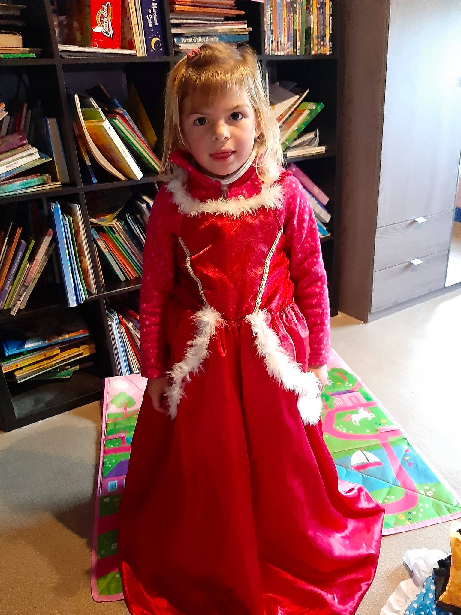 éléna a rejoint le concours — aidez-le/la à gagner de superbes lots ! book, bookcase, cabinetry, child, dress, event, fashion, fashion_design, flooring, formal_wear, furniture, magenta, one_piece_garment, peach, person, publication, shelf, shelving, sleeve, smile