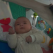 Liam a rejoint le concours — aidez-le/la à gagner de superbes lots ! baby, infant, play_mat, toy, clothing, cute, face, expression, indoor, floor, colorful, soft_texture, lying_down, child, person, smile, hand, room, decor, emojis