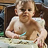 baby, child, high_chair, messy, food, spoon, face, hands, eating, indoor, person, cute, infant, expression, dining, seat, clutter, wooden_furniture, home, feeding
