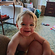 David is registered to the contest to win money with this photo: toddler, child, smiling, happy, indoor, living_room, carpet, furniture, lamp, television, toy, window, curtain, table, box, person, hair, skin, face, expression