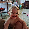 toddler, child, smiling, happy, indoor, living_room, carpet, furniture, lamp, television, toy, window, curtain, table, box, person, hair, skin, face, expression