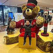Nolann a rejoint le concours — aidez-le/la à gagner de superbes lots ! child, christmas_tree, festive, holiday_decor, indoor, jacket, kid, mall, nutcracker, peace_sign, playful, posing, red_cushion, shopping_center, smiling, sneakers, teddy_bear, toy_soldier, winter_clothing, yellow_floor