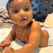 Hayan Sri Bandi is registered to the contest to win money with this photo: baby, infant, child, bed, blanket, bracelet, chain, cushion, curly_hair, dark_eyes, expression, face, indoors, jewelry, lying_down, portrait, skin, toddler, tousled_hair, young