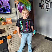 Parker joined the competition — help win amazing prizes! balloon, birthday, blonde_hair, cabinet, carpet, casual_clothing, child, decoration, family_photos, happy, indoor, jeans, living_room, number_8, pumpkin, smiling, sock, television, toy, tshirt
