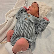 Astor joined the competition — help win amazing prizes! newborn, baby, sleeping, infant, portrait, knitted_outfit, gray_clothing, white_hat, blanket, cozy, indoors, bed, peaceful, resting, closed_eyes, tiny_hands, bare_legs, socks, candid, family_photo