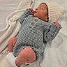 newborn, baby, sleeping, infant, portrait, knitted_outfit, gray_clothing, white_hat, blanket, cozy, indoors, bed, peaceful, resting, closed_eyes, tiny_hands, bare_legs, socks, candid, family_photo