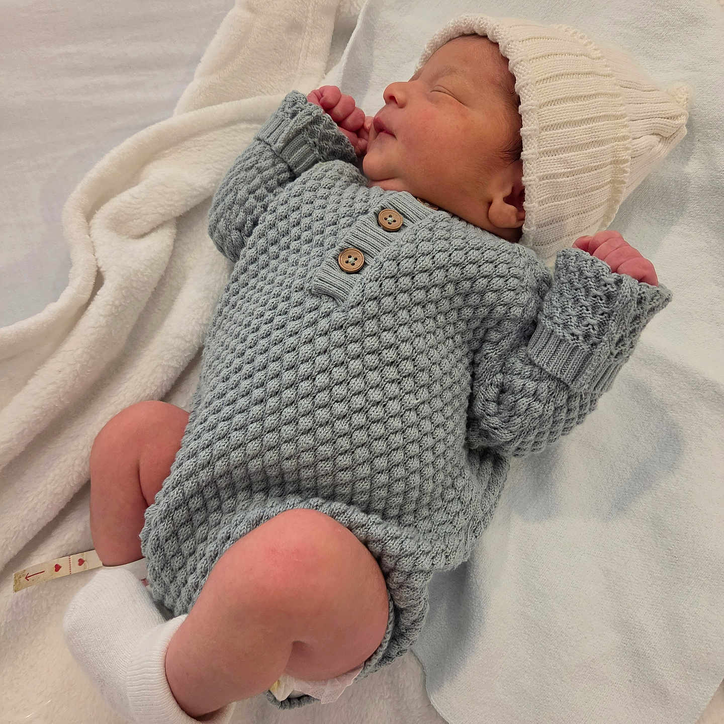 Astor joined the competition — help win amazing prizes! newborn, baby, sleeping, infant, portrait, knitted_outfit, gray_clothing, white_hat, blanket, cozy, indoors, bed, peaceful, resting, closed_eyes, tiny_hands, bare_legs, socks, candid, family_photo