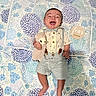 Mario joined the competition — help win amazing prizes! baby, infant, smiling, laughing, stuffed_animal, plush_toy, suspenders, shorts, shirt, bow_tie, quilt, floral_pattern, milestone_card, four_months, lying_down, happy, cute, child, indoors, portrait