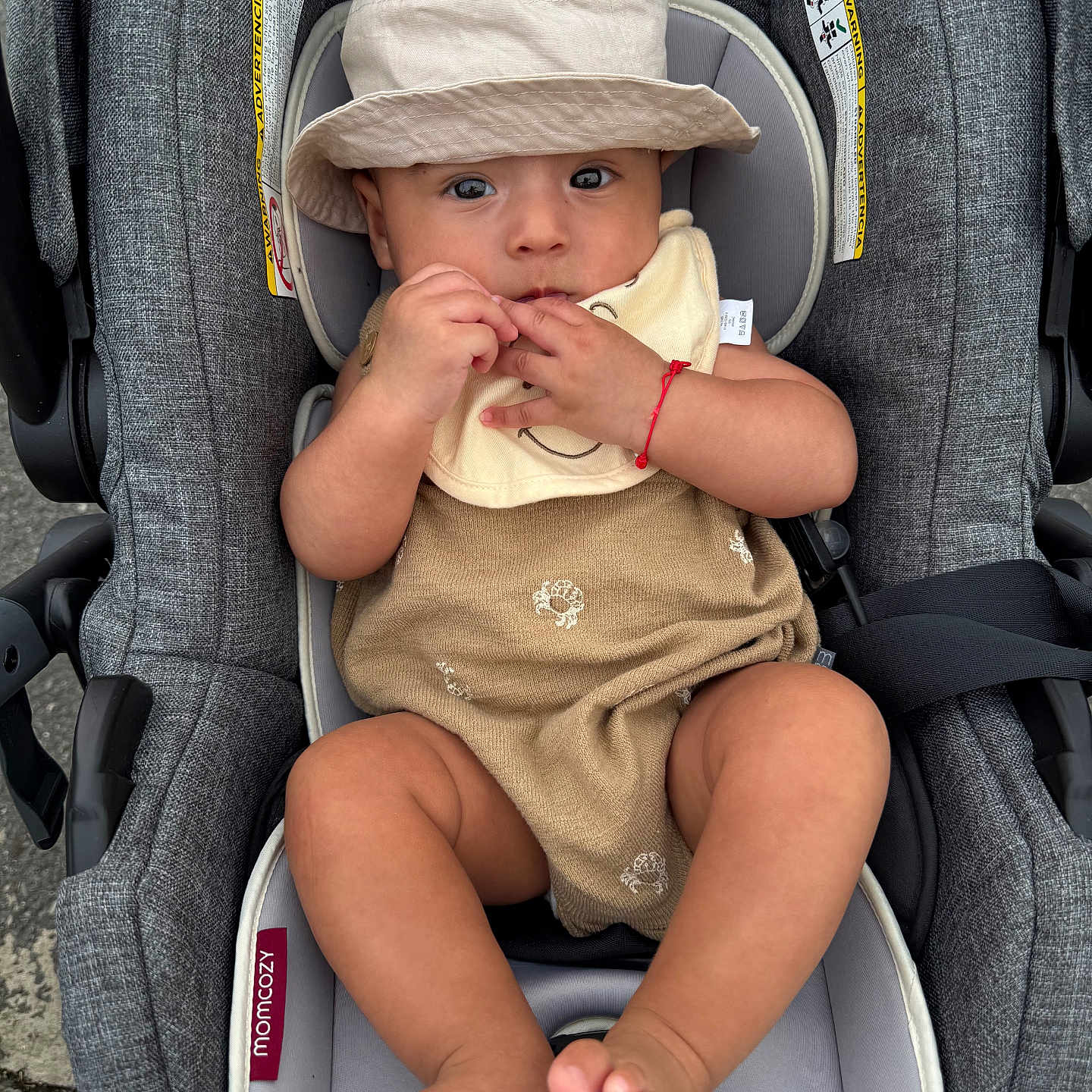 Mario joined the competition — help win amazing prizes! baby, child, car_seat, hat, bib, romper, sitting, cute, infant, legs, toes, fingers, curious, clothing, seatbelt, gray, outdoor, person, portrait, closeup