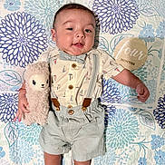 Mario joined the competition — help win amazing prizes! baby, infant, child, stuffed_animal, toy, quilt, floral_pattern, clothing, bow_tie, suspenders, milestone_sign, wooden_sign, cute, smiling, lying_down, indoor, portrait, happy, young_child, celebration