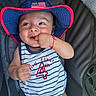 baby, child, hat, american_flag, onesie, striped_clothing, car_seat, smiling, hand_in_mouth, blue_hat, red_trim, cute, infant, portrait, happy, casual, indoors, baby_boy, closeup, seatbelt