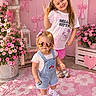 bows, children, flower_pots, flowers, garden, girls, heart_shaped_sunglasses, hello_kitty, outdoor, overalls, peace_sign, pink_theme, playful, portrait, rug, shorts, smiling, sneakers, sunglasses, toddler
