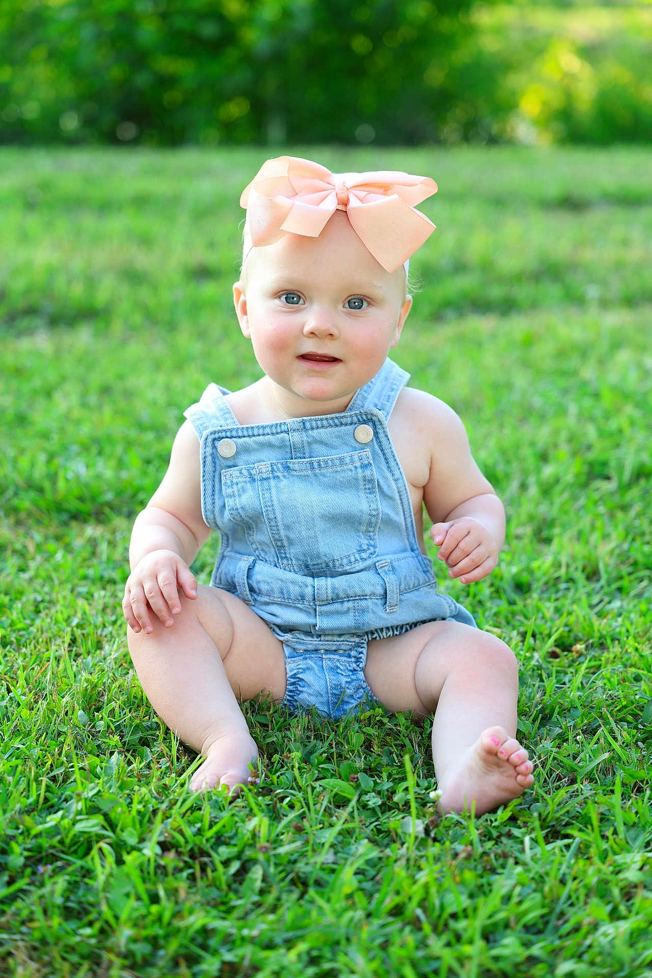 Kensley is registered to the contest to win money with this photo: toddler, child, baby, outdoor, grass, greenery, denim_overalls, bow, headwear, barefoot, sitting, cute, portrait, nature, sunlight, blue_eyes, pink_toenails, summer, happy, innocent