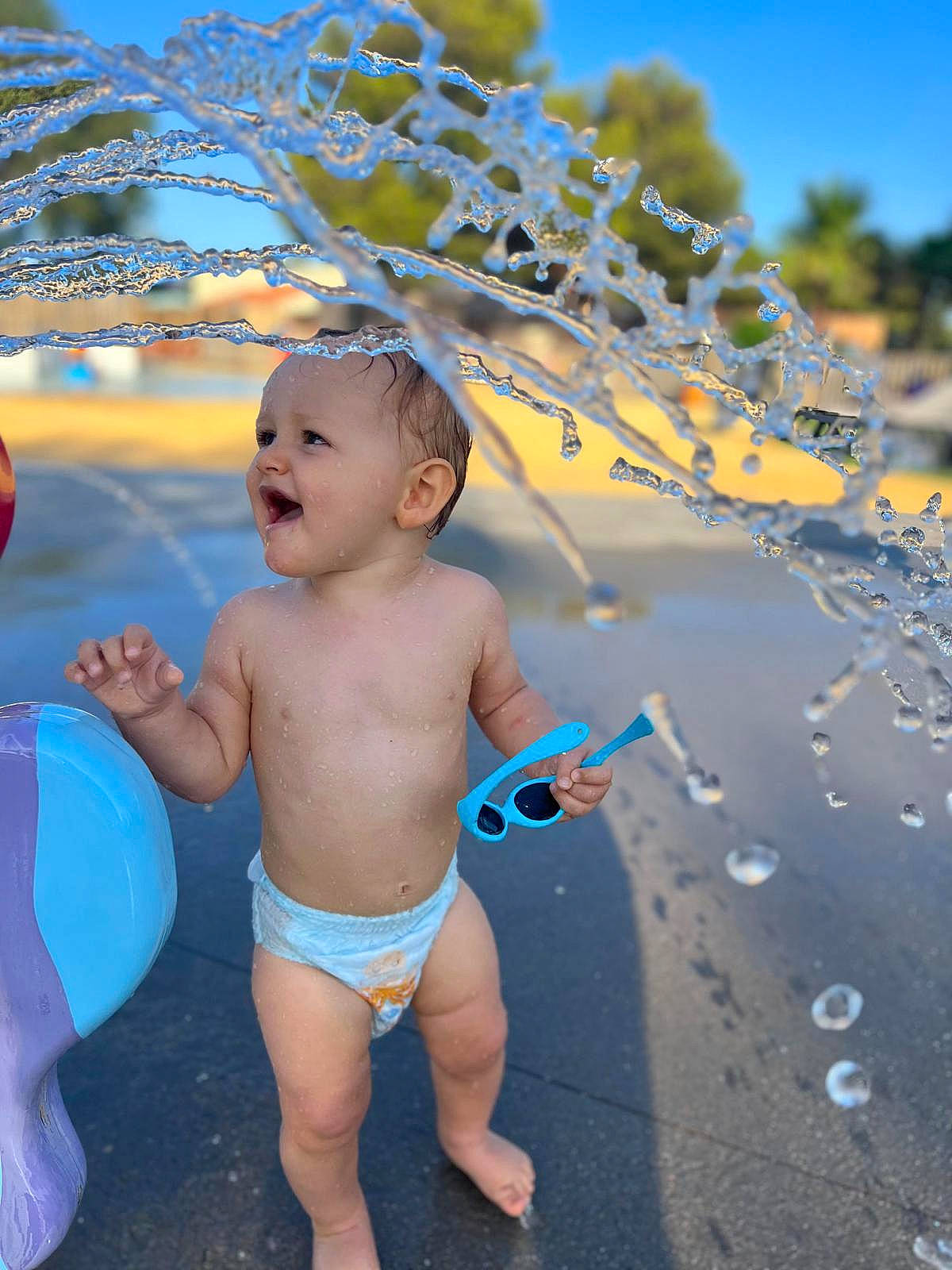 Baptiste a rejoint le concours — aidez-le/la à gagner de superbes lots ! abdomen, azure, baby, barechested, chest, electric_blue, fun, gesture, grass, happy, landscape, leisure, navel, people_in_nature, person, sand, sky, summer, swimwear, toddler