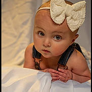 Ronni joined the competition — help win amazing prizes! adorable, baby, bow, child, closeup, clothing, curious, cute, denim, expression, eyes, face, hands, headband, indoor, infant, overalls, portrait, skin, soft_lighting