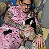 Maple Mae is registered to the contest to win money with this photo: blanket, casual, comfort, couch, dog, face, glasses, hand, home, indoor, pajamas, patterned_fabric, person, pet, pillow, relaxing, resting, seated, small_dog, tattoo