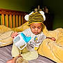 baby, bed, bodypart, bread, cap, clothing, couch, crib, face, finger, food, furniture, hand, hat, head, indoors, infantbed, person, photography, portrait