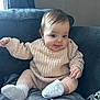 Isabella joined the competition — help win amazing prizes! baby, child, infant, knit_sweater, pants, socks, couch, furniture, indoor, smiling, cute, happy, face, person, seated, cozy, home, soft_lighting, young, portrait