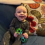 Miles joined the competition — help win amazing prizes! baby, child, smiling, toy, pajamas, couch, pillow, blanket, indoor, happy, sitting, face, person, infant, colorful, patterned_pillow, hand, furniture, home, cozy