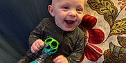Miles joined the competition — help win amazing prizes! baby, smiling, toy, onesie, couch, pillow, blanket, indoor, child, happy, home, sitting, face, person, clothing, furniture, play, infant, cute, joyful