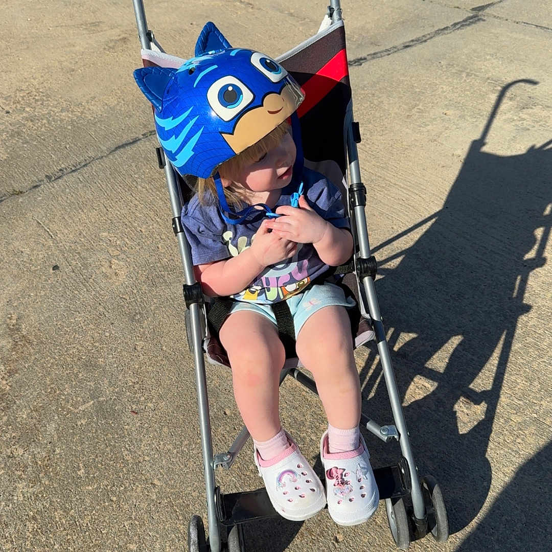 Sophia is registered to the contest to win money with this photo: alloywheel, baby, car, carwheel, clothing, face, footwear, hat, head, machine, person, photography, portrait, shoe, shorts, spoke, tire, transportation, vehicle, wheel