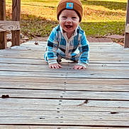 Khoen joined the competition — help win amazing prizes! baby, child, crawling, outdoor, wooden_deck, beanie, blue_clothing, smiling, happy, grass, sunlight, nature, face, person, infant, playful, cute, young_child, casual_wear, daylight