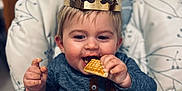 Liam participe au concours pour gagner de l'argent avec cette photo : baby, child, crown, high_chair, waffle, food, snack, eating, happy, smiling, indoor, person, clothing, seat, face, hand, crumbs, cute, young, portrait