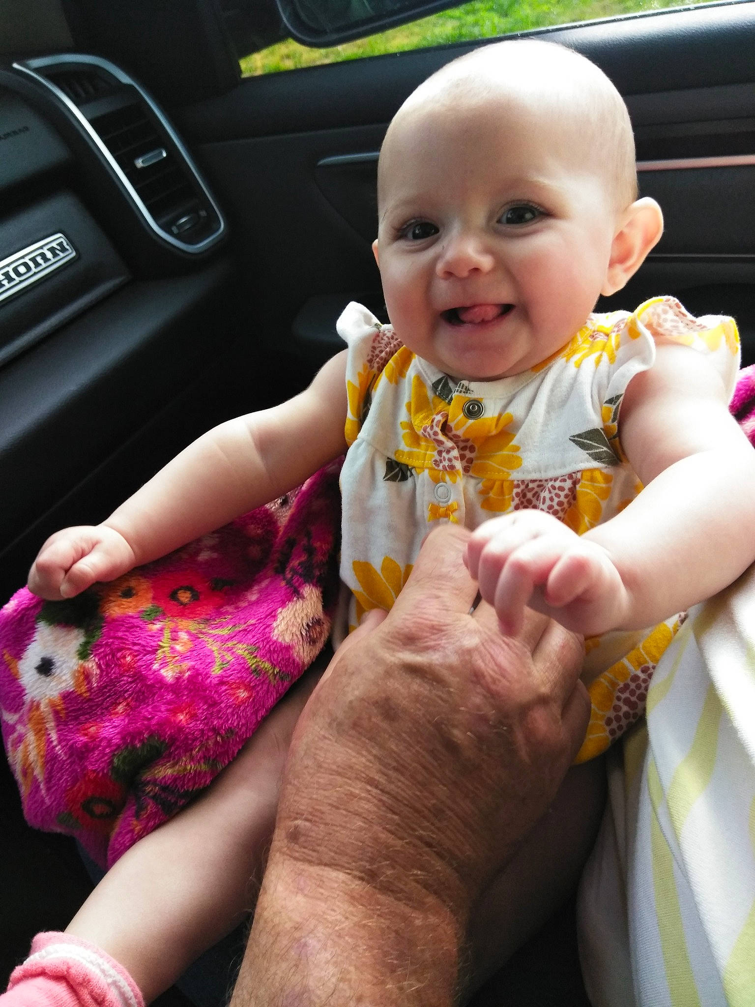 Aniya is registered to the contest to win money with this photo: arm, automotive_design, baby, baby_toddler_clothing, dress, facial_expression, finger, fun, gesture, hand, happy, motor_vehicle, mouth, person, pink, skin, smile, steering_wheel, thumb, toddler