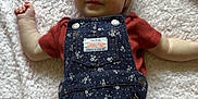 Addison is registered to the contest to win money with this photo: baby, infant, headband, overalls, denim, floral_pattern, blanket, soft_texture, smile, face, skin, arms, legs, cute, lying_down, clothing, child, indoors, portrait, happy