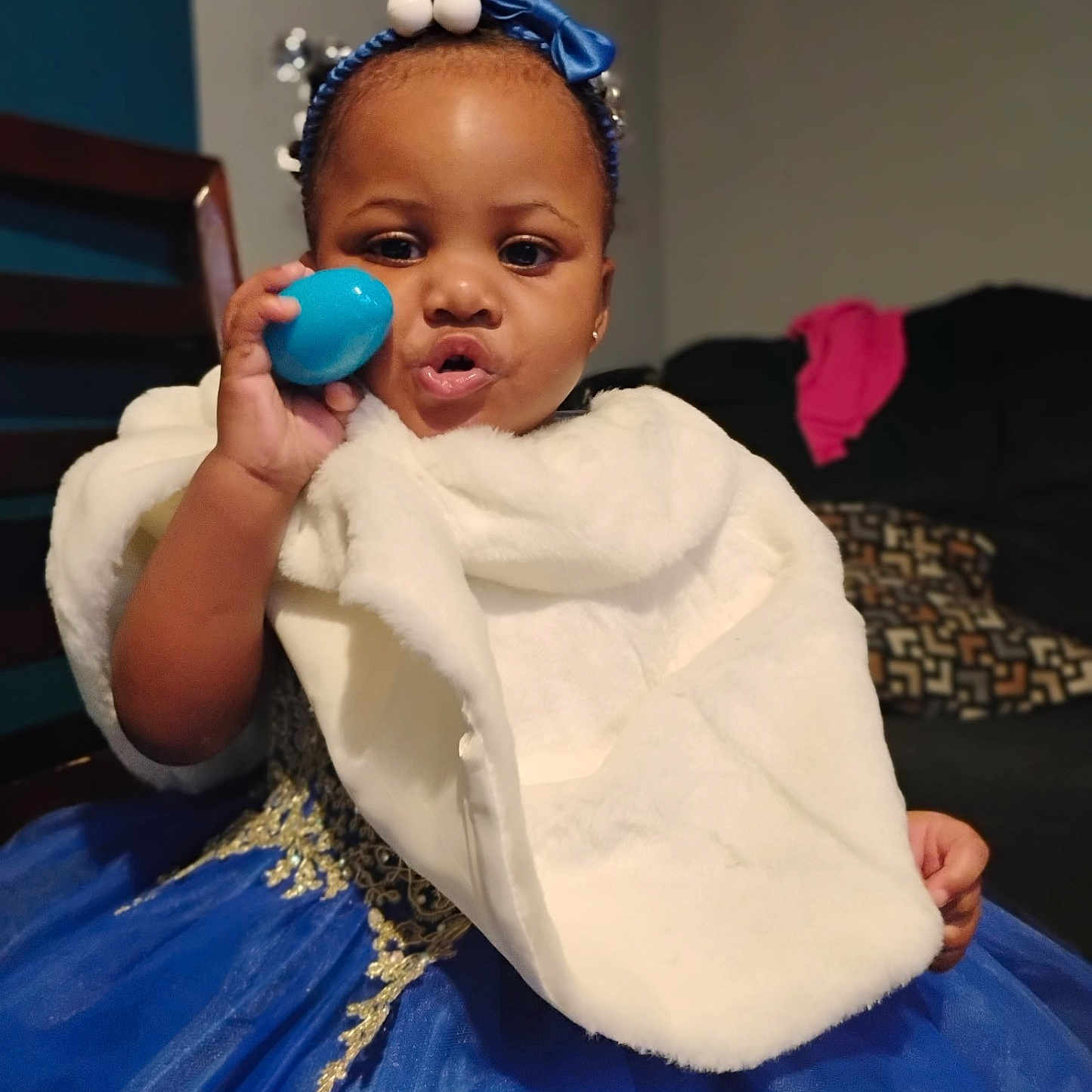Kelaia joined the competition — help win amazing prizes! toddler, child, dress, blue_dress, fur_shawl, headband, blue_headband, indoor, living_room, sofa, chair, pillow, person, cute, playful, face, hand, toy, smile, portrait