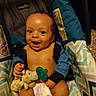 baby, child, infant, smiling, happy, portrait, car_seat, sitting, pacifier, stuffed_animal, giraffe_toy, diaper, blue_clothing, striped_fabric, indoor, close_up, face, baby_carrier, safety_label, photography