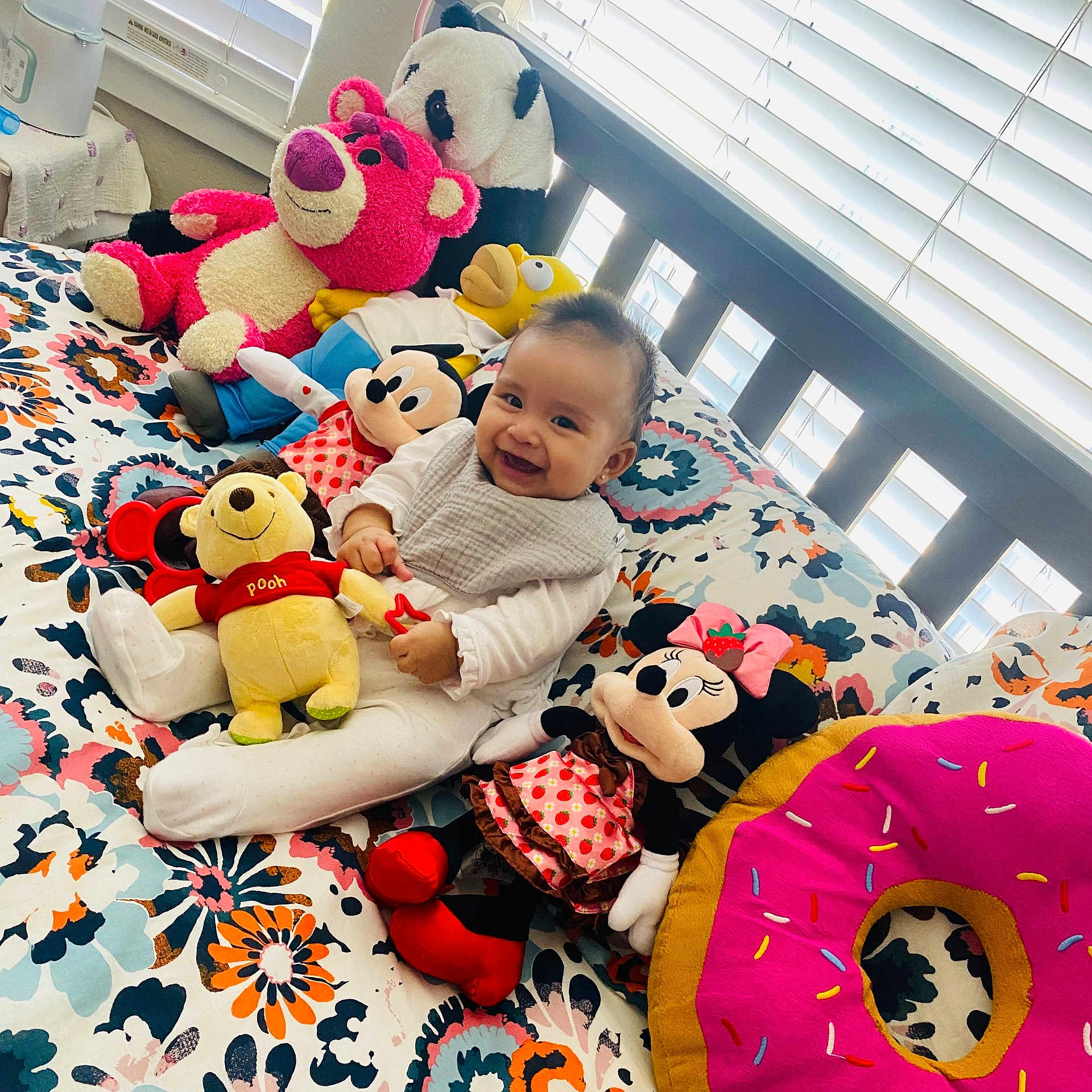 Andrea is registered to the contest to win money with this photo: baby, bed, child, colorful, cute, floral_bedspread, happy, indoors, mickey_mouse, minnie_mouse, pink_donut, playful, plush_toy, sitting, smiling, soft_lighting, stuffed_animal, toy_collection, window_blinds, winnie_the_pooh