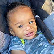 Namir joined the competition — help win amazing prizes! toddler, child, smile, curly_hair, stroller, blue_shirt, camo_pattern, seat, sunlight, happy, portrait, baby, infant, outdoor, casual_clothing, closeup, person, young_child, relaxing, daylight