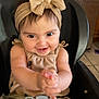 Octavia is registered to the contest to win money with this photo: baby, child, smiling, clapping, headband, bow, high_chair, straps, indoors, kitchen, fridge, drawing, happy, cute, infant, person, clothing, seatbelt, toddler, home