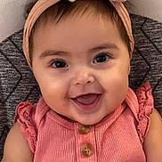Octavia is registered to the contest to win money with this photo: baby, child, smiling, headband, bow, pink_clothing, buttons, happy, portrait, face, infant, cute, young_child, sitting, closeup, indoors, soft_background, patterned_fabric, skin, eyes