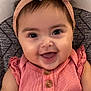 baby, child, smiling, headband, bow, pink_clothing, buttons, happy, portrait, face, infant, cute, young_child, sitting, closeup, indoors, soft_background, patterned_fabric, skin, eyes