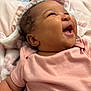 baby, infant, smiling, laughing, pink_clothing, blanket, curly_hair, cute, happy, child, indoors, person, portrait, soft_texture, cozy, skin, head, face, newborn, toddler