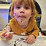 Nathalia is registered to the contest to win money with this photo: toddler, child, highchair, messy, chocolate, crumbs, face, mouth, hands, spoon, sweater, yellow, indoor, table, food, cute, expression, young, person, eating
