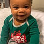 baby, smile, child, pajamas, green_shirt, patterned_pants, gift_box_pattern, happy, indoor, blanket, soft, cute, portrait, seated, infant, face, eyes, hands, cozy, holiday