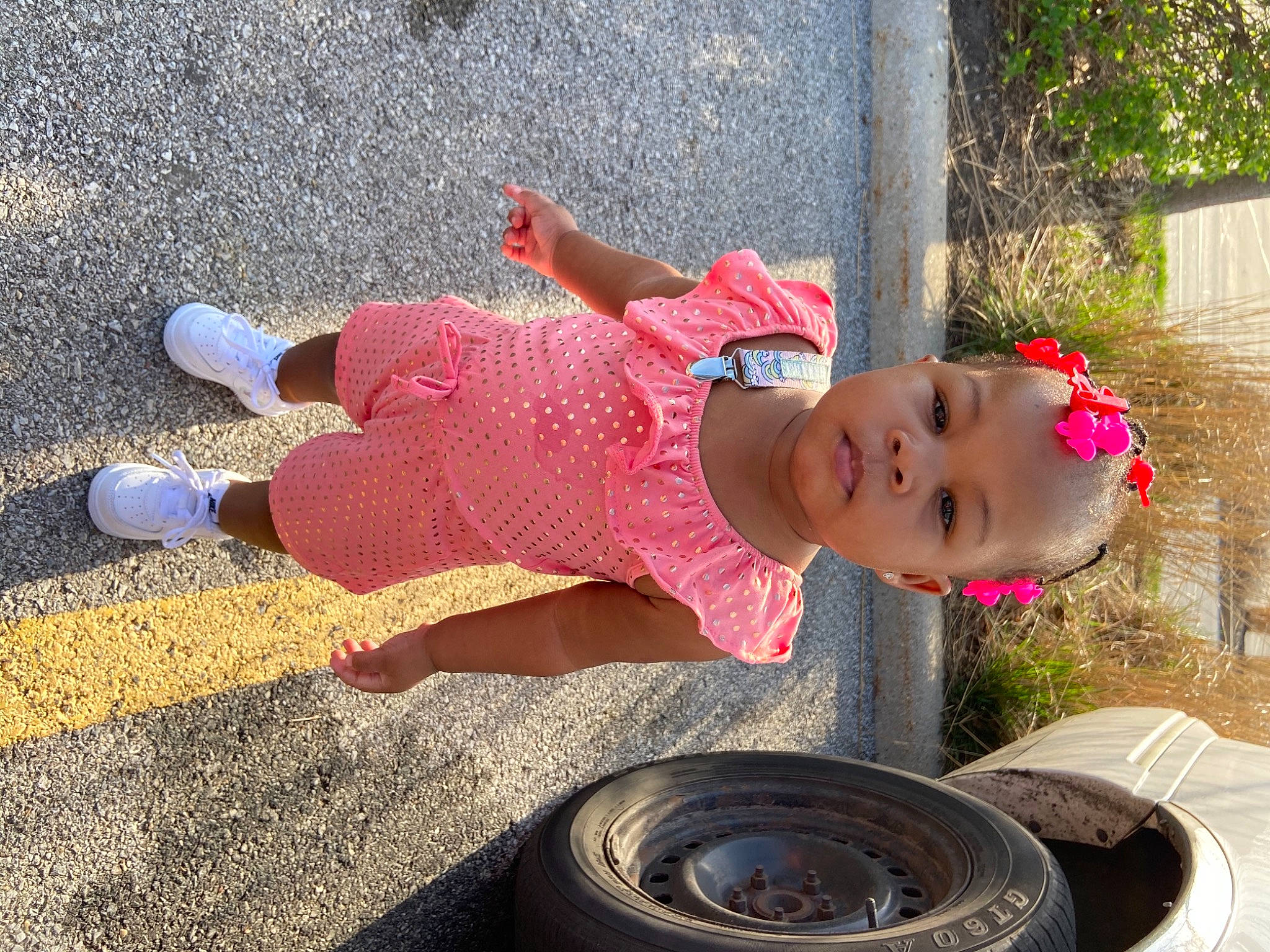 Alaysia is registered to the contest to win money with this photo: asphalt, automotive_tire, automotive_wheel_system, baby, baby_toddler_clothing, child, fun, grass, hat, hubcap, human_leg, magenta, person, plant, synthetic_rubber, tire, tire_care, toddler, tread, water