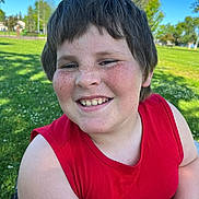 Adian is registered to the contest to win money with this photo: blue_sky, casual_clothing, cheerful, child, closeup, daylight, face, freckles, grass, happy, nature, outdoor, park, person, portrait, red_shirt, smiling, summer, sunny, trees