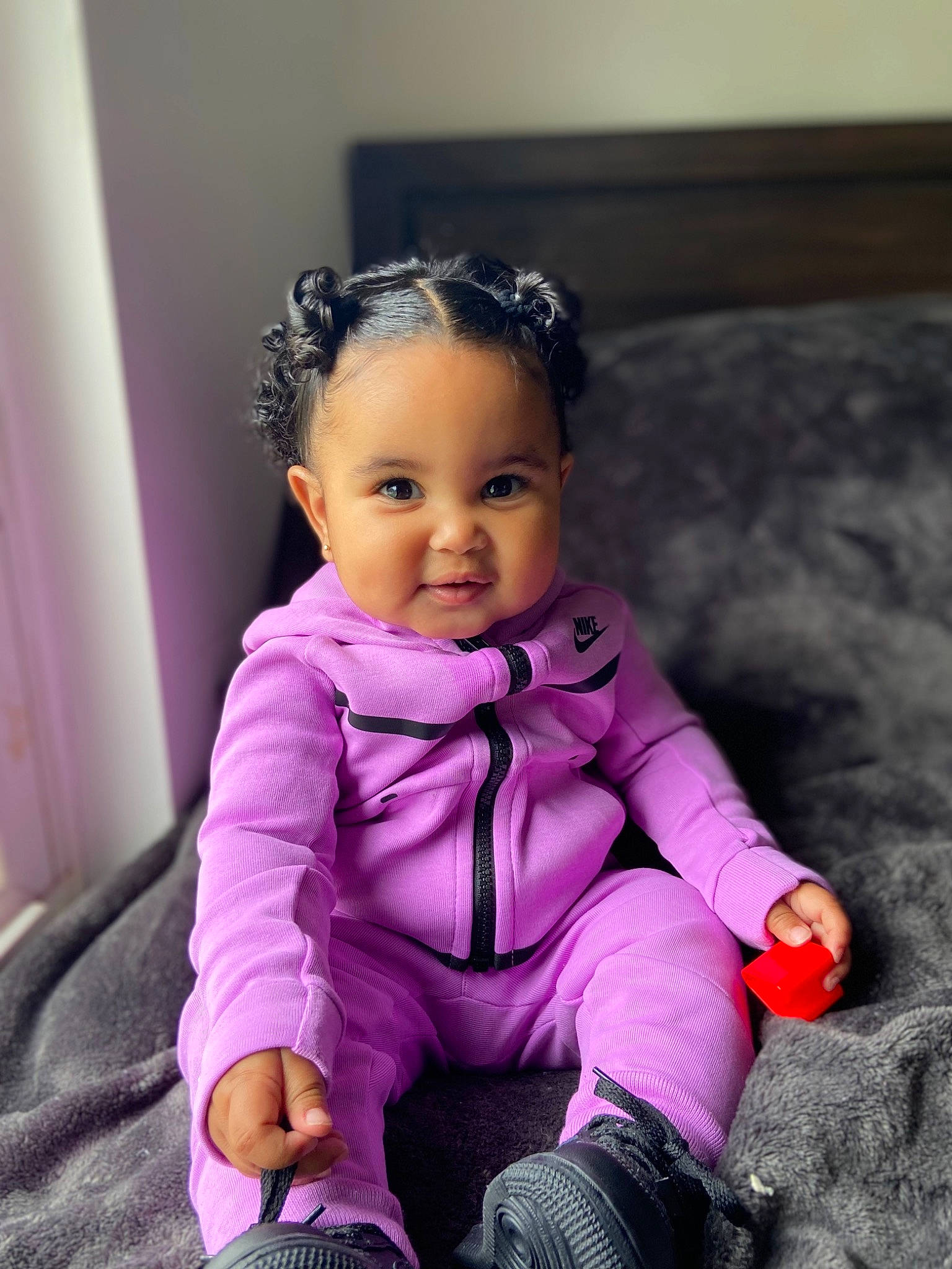 Amina is registered to the contest to win money with this photo: baby, baby_toddler_clothing, cheek, child, curtain, eye, face, flash_photography, fun, gesture, happy, head, magenta, person, pink, purple, sitting, sleeve, smile, toddler